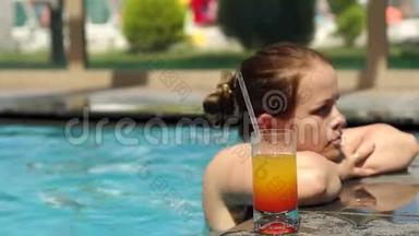 一个快乐的女孩在游泳池里游泳，喝一杯清爽的鸡尾酒。